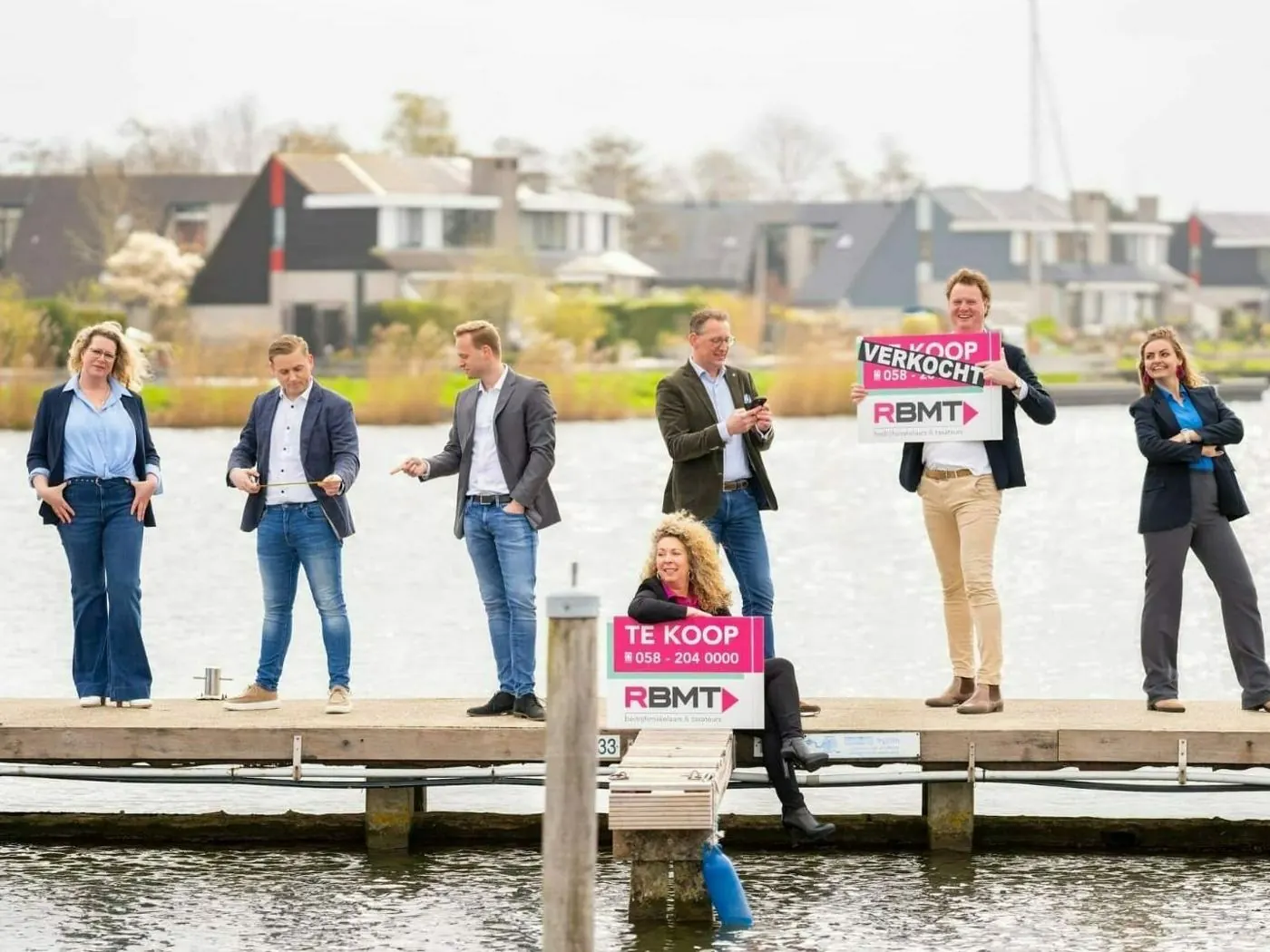 Het team van RBMT op een steiger met te-koop- en verkocht-borden